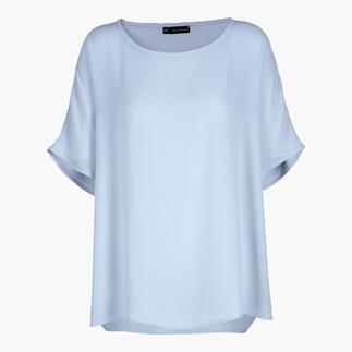 Lichtblauwe T-shirt-blouse met een losse pasvorm en korte mouwen op een neutrale achtergrond.
