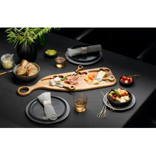 Design serveerplank van acaciahout met kaas, fruit en snacks op een donkere tafel.