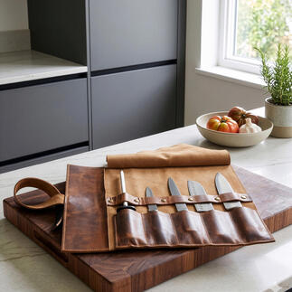 Messentas in buffelleer met keukenmessen op een houten snijplank.