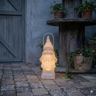 LED tuinkabouter met zacht licht, geplaatst op een stenen vloer naast plantenpotten.