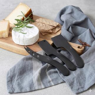 Drie kaasmesjes op een houten plank met snacks
