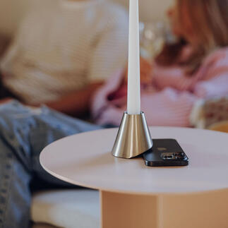 Kaars in metalen houder op tafel, achtergrond met mensen.