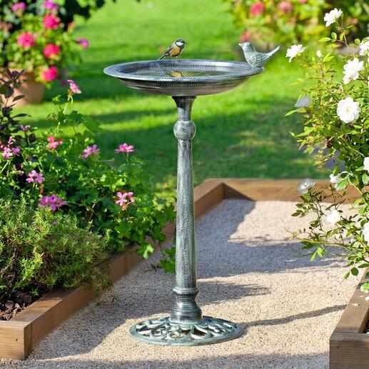 Victoriaans vogelbad met vogel in een bloeiende tuin