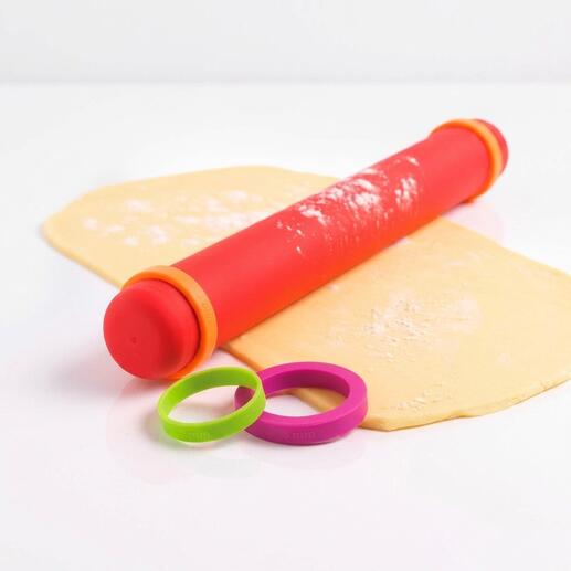 Vario-deegroller van silicone in rood met verwisselbare ringen op een deegblad.