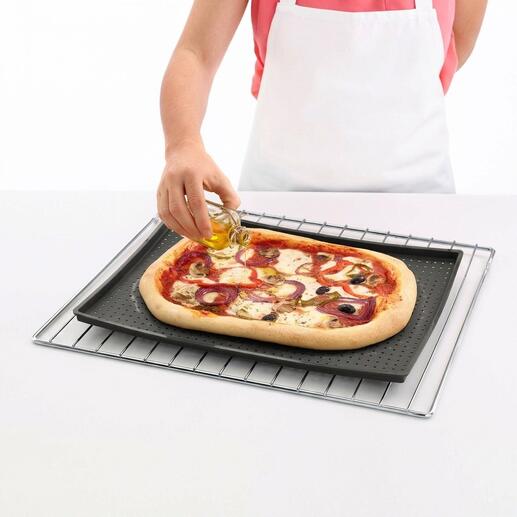 Persoon besprenkelt een pizza met olie op een krokante bakmat