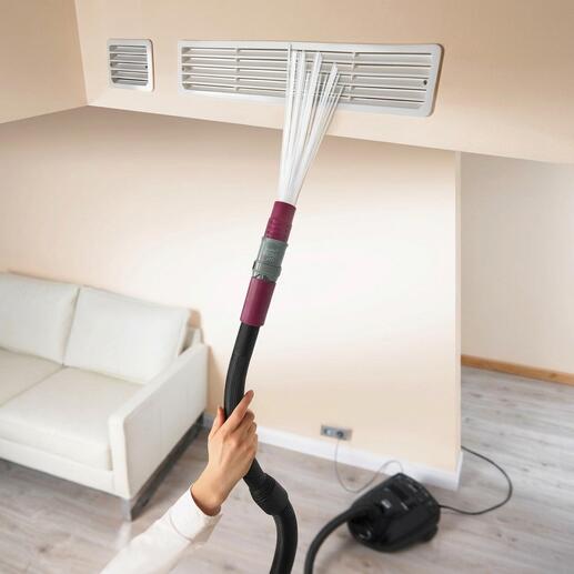 Hand met stofzuigeraccessoire dat een luchtopening schoonmaakt.