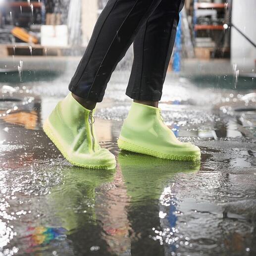 Persoon met lichtgroene regenoverschoenen staat in een plas.