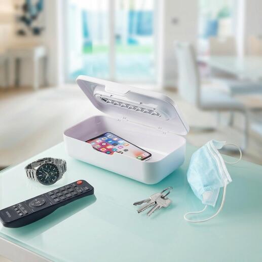 UV-C-straalsterilisator 2-in-1 met smartphone en dagelijkse voorwerpen op een tafel.