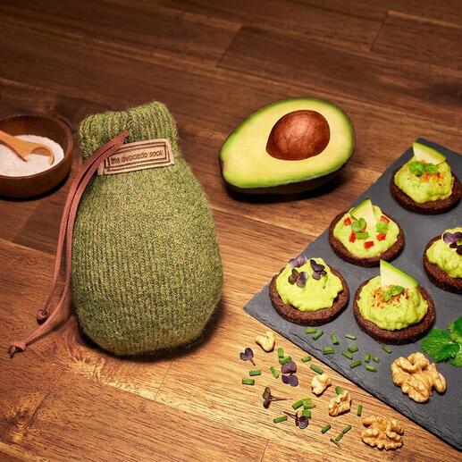 Avocado Sock® samen met avocado en snacks op een houten tafel.