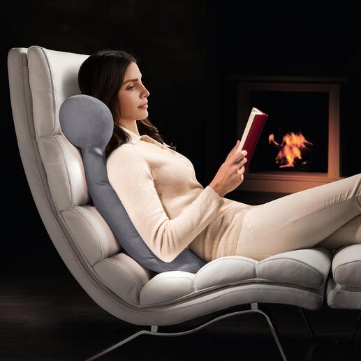 Vrouw ontspant in een fauteuil en leest met HEFEL lees kussen.
