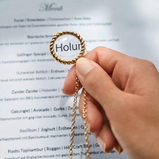 Hand houdt vergrootglas aan een gouden ketting boven een menu.
