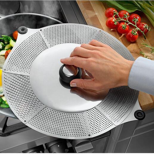 Hand die een universele spatschermdeksel op een pan met groenten en een ei op een fornuis plaatst