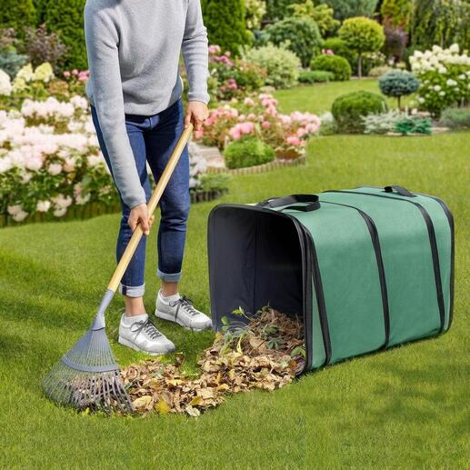 Persoon die bladeren in een vierkante tuinafvalverzamelaar op het gras veegt
