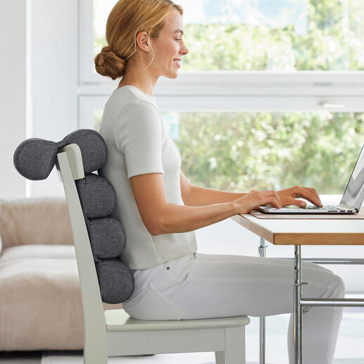 Vrouw zit met flexi-rolkussen aan een bureau en werkt op de laptop.