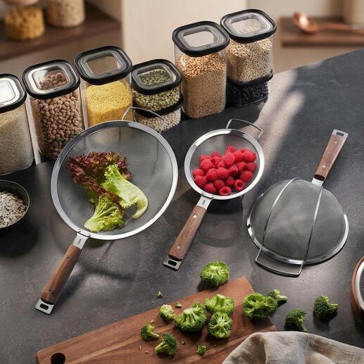 Drie zeefjes met houten handvatten op een keukentafel.
