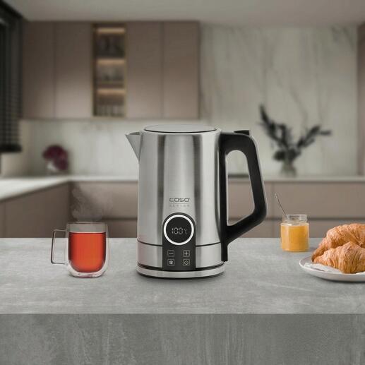 Moderne roestvrijstalen waterkoker op een aanrecht met een kopje thee en een croissant.