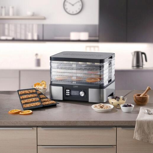 Voedseldroger op een tafel met verschillende gezonde snacks en ingrediënten.