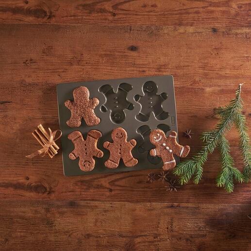 Ontwerpvorm voor peperkoekmannen met gebakken peperkoekmannen op een tafel.