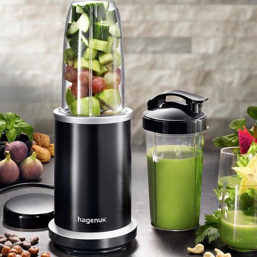 Smoothie-blender met fruit en groenten in de kom en een beker ernaast
