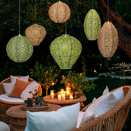 Zes weerbestendige lampions met zonne-energie en LED's rond een tuinlounge.