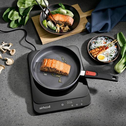 Ultradun inductiekookplaat met een pan en gebakken zalm.