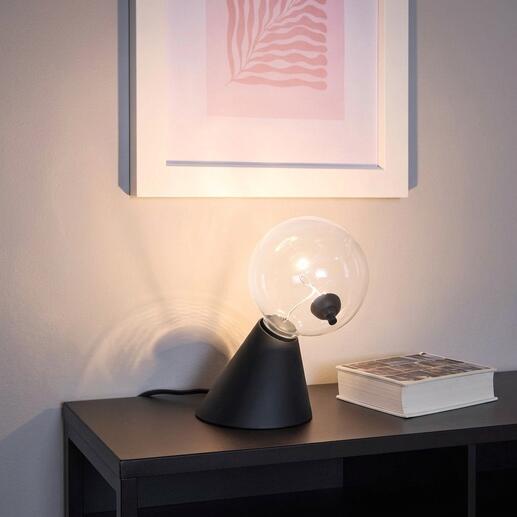 Tafel lamp Satellite met heldere glazen bol en zwarte voet op een plank.