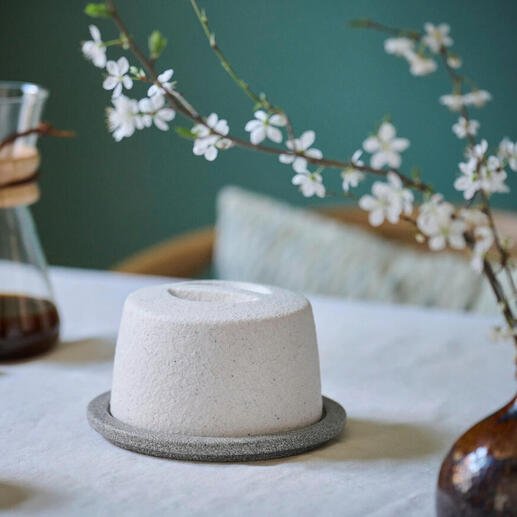 Keramische botervorm op een tafel met bloemen en koffiepot.