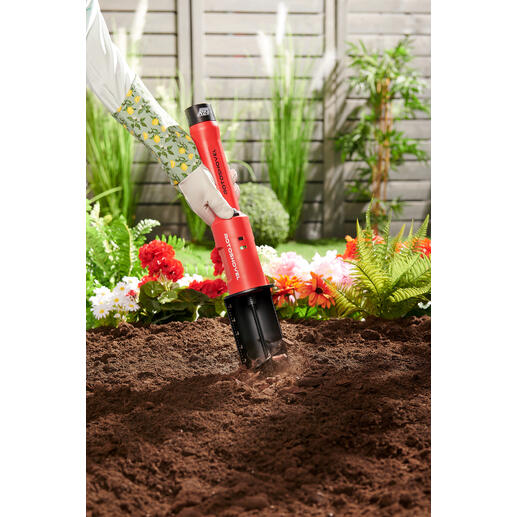 Accu-tuinboor Accu-tuinboor in de aarde met bloemen op de achtergrond