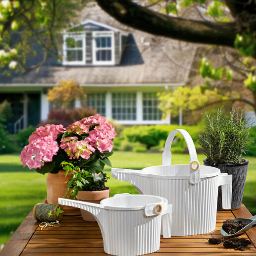 Twee gieters in wit en bloemen op een tafel in de tuin
