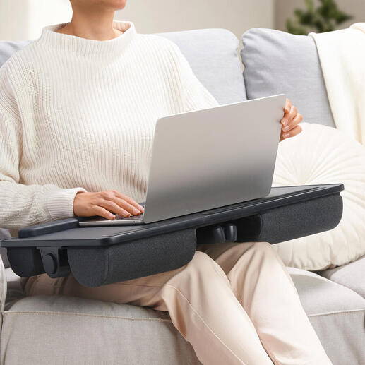 Persoon met een 2-in-1 laptopkussen op schoot dat als tafel fungeert.