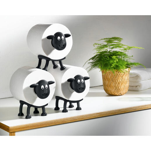 Drie toiletpapierhouders in de vorm van schapen op een tafel.