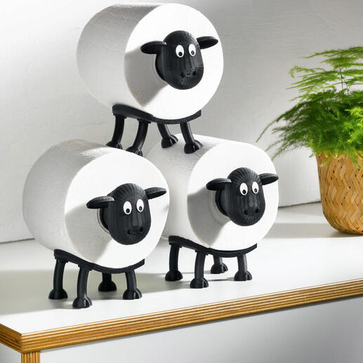 Drie toiletpapierhouders in de vorm van schapen op een tafel.