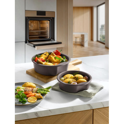 Twee keltenpotten met groenten en aardappelen op een houten bord in een moderne keuken.