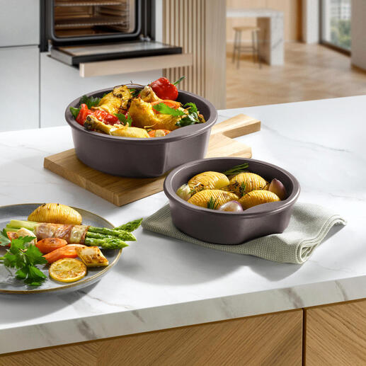 Twee keltenpotten met groenten en aardappelen op een houten bord in een moderne keuken.