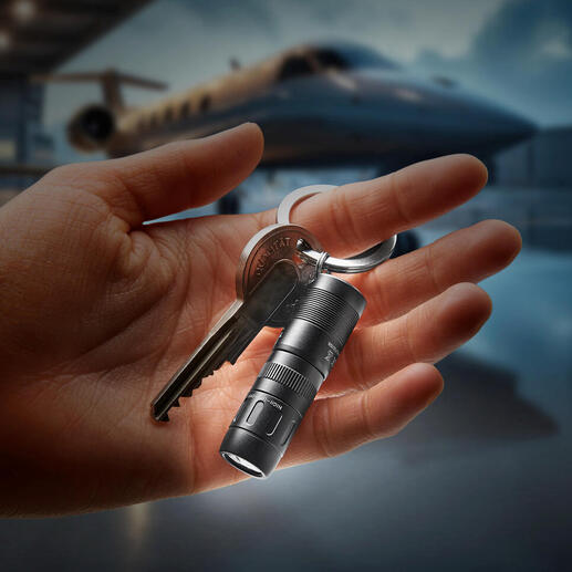 Hand houdt magnetische mini-zaklamp met sleutelring vast, licht straalt in het donker.