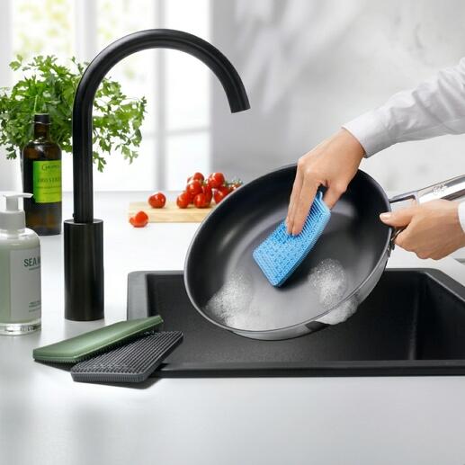 Persoon reinigt een pan met een blauwe siliconen afwasborstel.