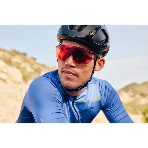 Fietser met rode sportzonnebril en zwarte helm op een pad.