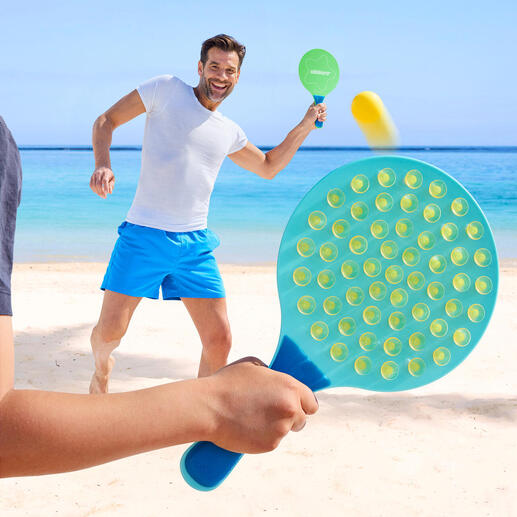 Man speelt op het strand met een ovale paddle en raakt de bal.