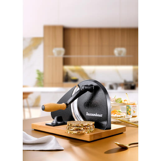 Handmatige broodsnijder op een houten plank met vers gesneden brood.