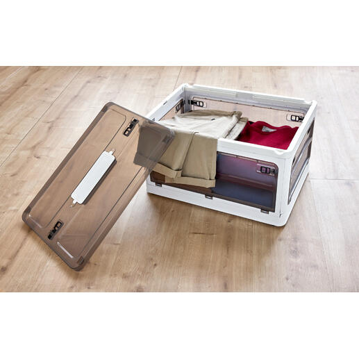 Open opbergdoos met kleding op houten vloer.