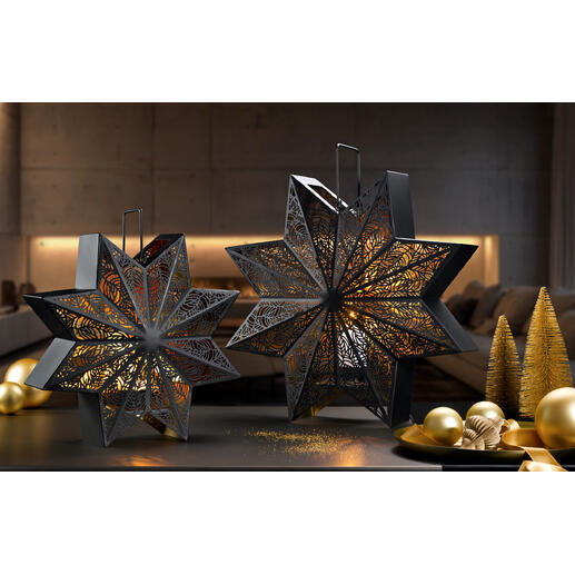 Twee decoratieve lantaarns in stervorm op een tafel met gouden kerstballen.