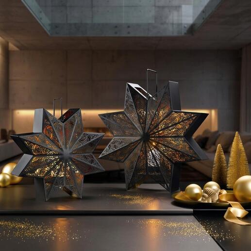Twee decoratieve lantaarns in stervorm op een tafel met gouden kerstballen.