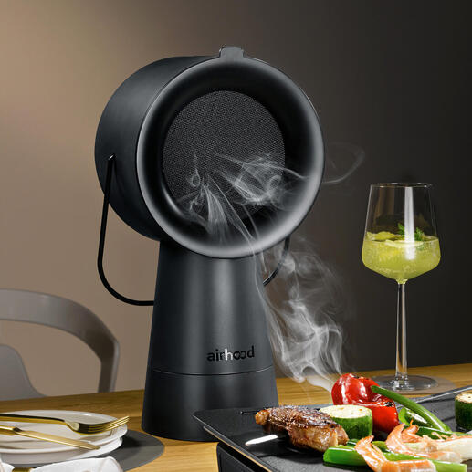 Airhood 2.0 in het zwart, rokend grillapparaat op tafel met groenten en vlees.