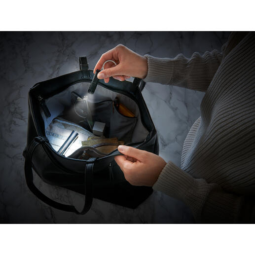 Twee handen houden een slimme micro-zaklamp in een tas