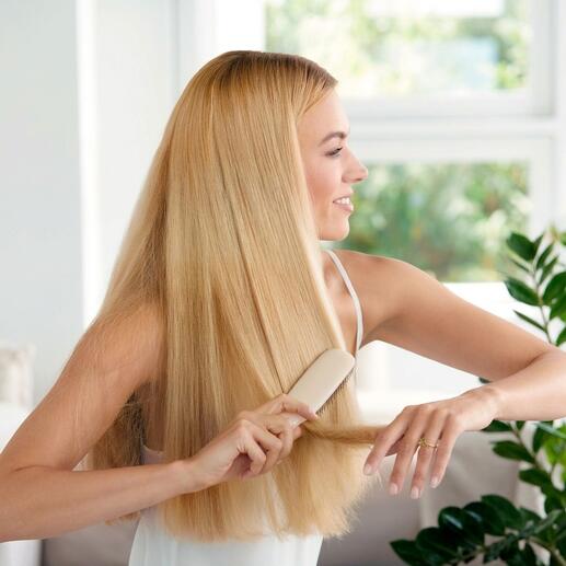 Vrouw met blond haar borstelt haar haar met een haarborstel op een lichte achtergrond.