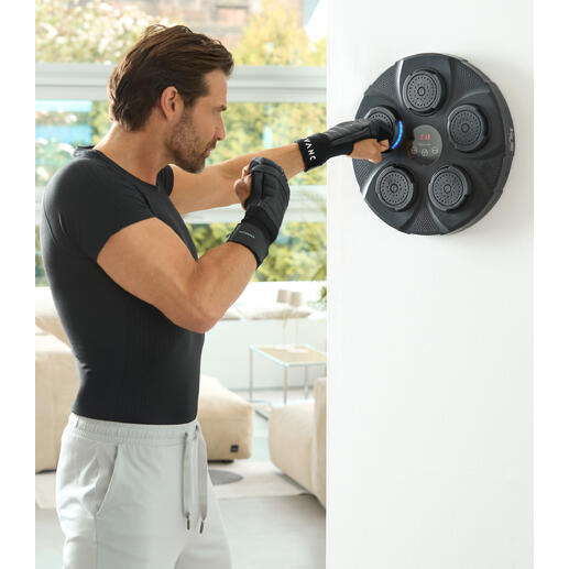 Man slaat met handen op wandbox trainer, fitnessruimte met heldere ramen op de achtergrond.
