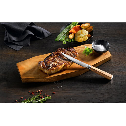 Damast steakmes op houten snijplank met gegrild steak en groenten.