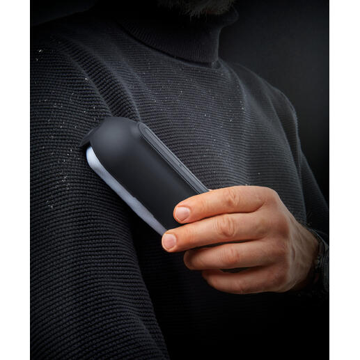 Ultragehechte pluisroller in de hand van een man, met pluisjes op een trui.