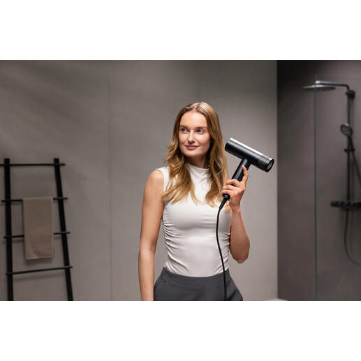 Vrouw houdt een zwarte föhn vast in een moderne badkamer.