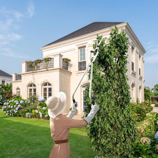 Vrouw snoeit met een multi-angle takkenschaar hoge planten in de tuin.